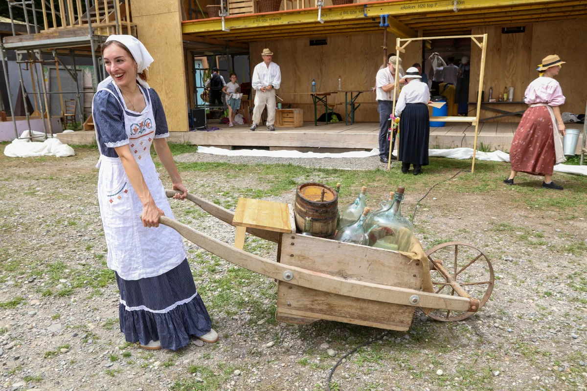 Die Fabrikarbeiterin Emma (Angelina Rieder) wird im zweiten Teil des Stücks den Streik in der Maggi-Fabrik anführen. Frau steht vor einer Schubkarre.